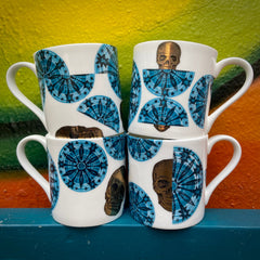 Set of four ceramic mugs with blue Stardust patterns and gold skull designs on a colorful background